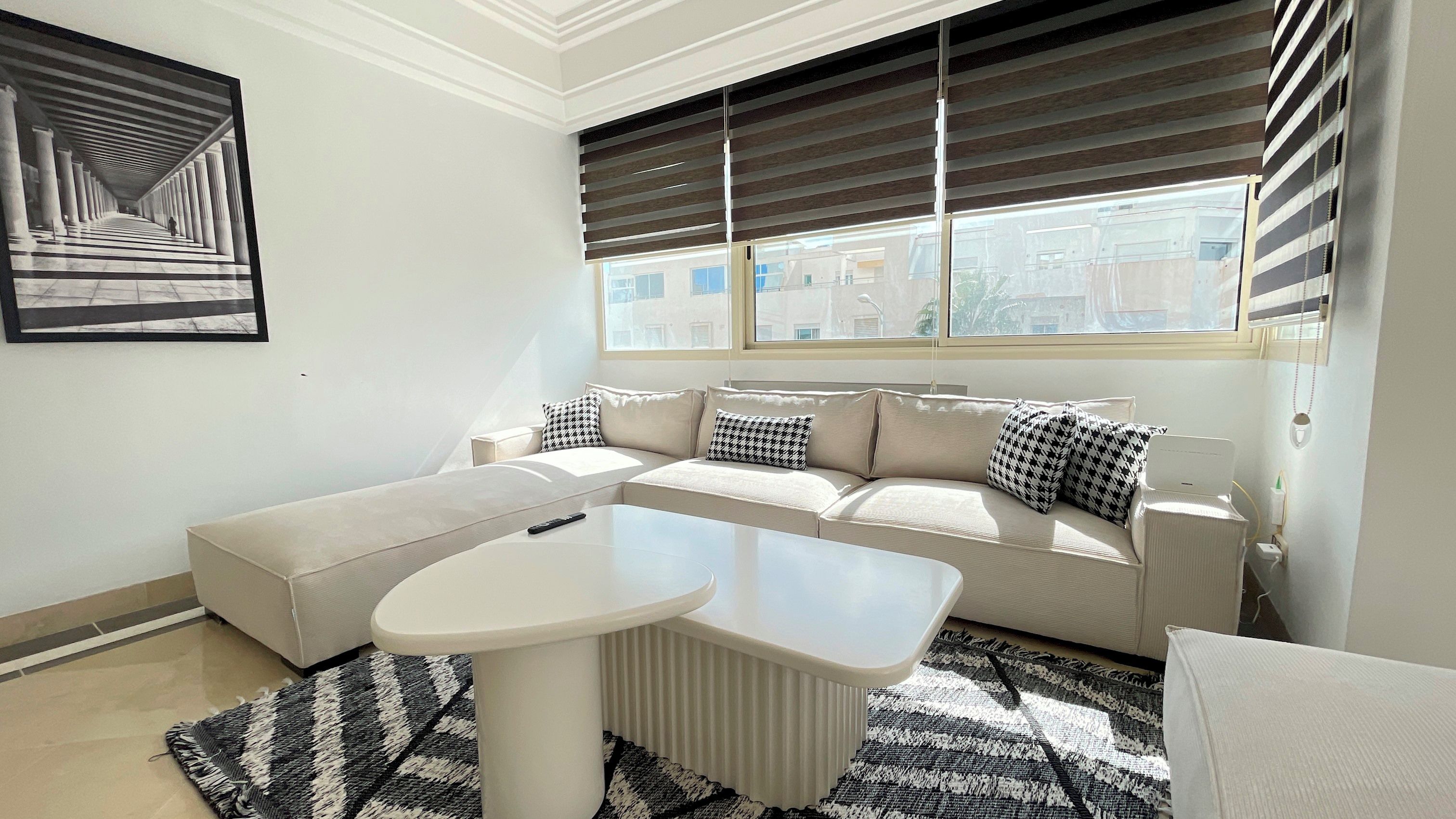 Un salon moderne avec un canapé d’angle, une table basse ronde et un tapis à motifs.