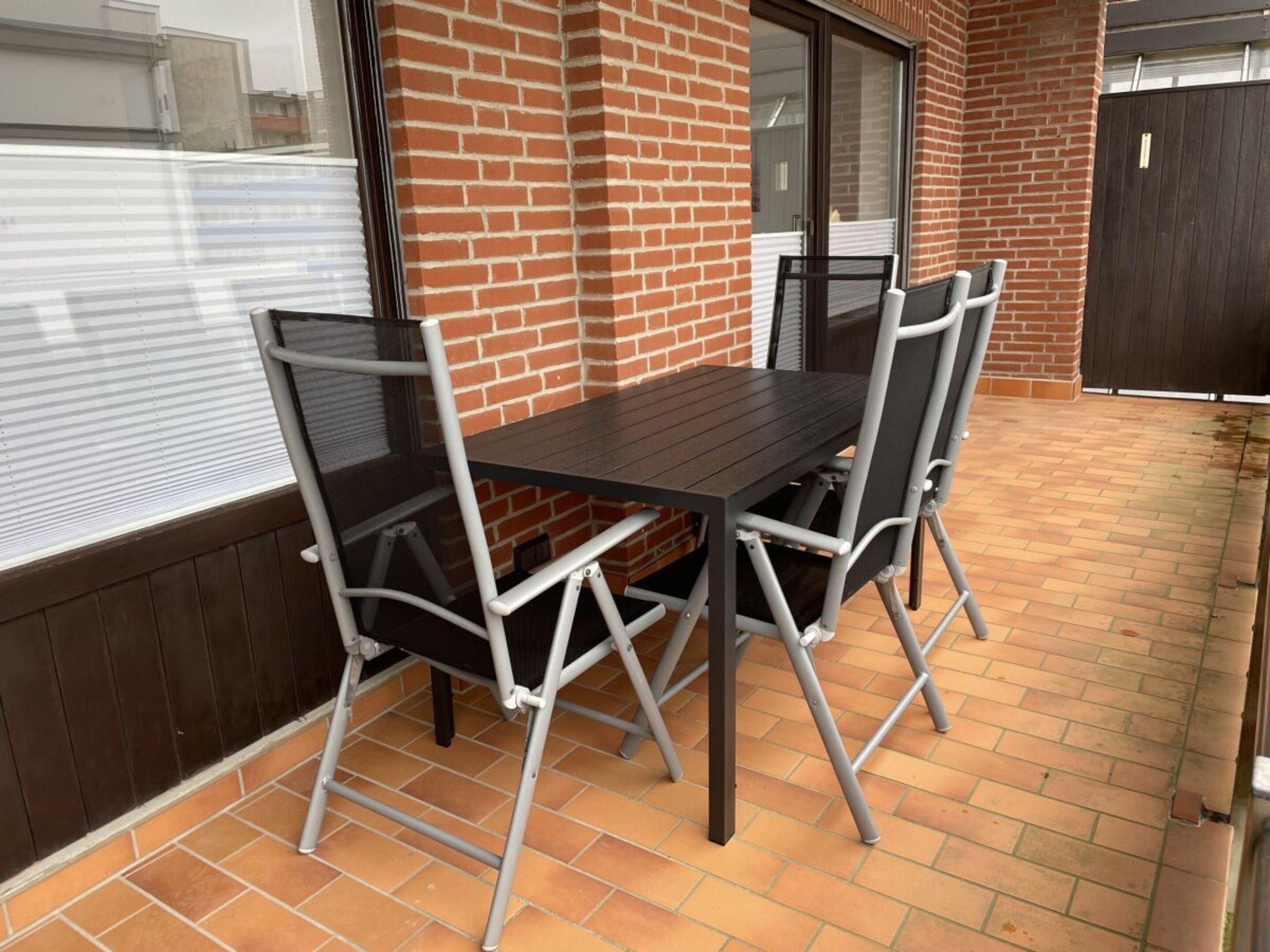 A patio area with a brick wall, a sliding glass door, and a table with four chairs.