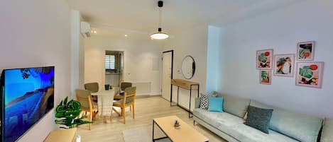 A modern living room with a sofa, coffee table, TV, and artwork on the wall.