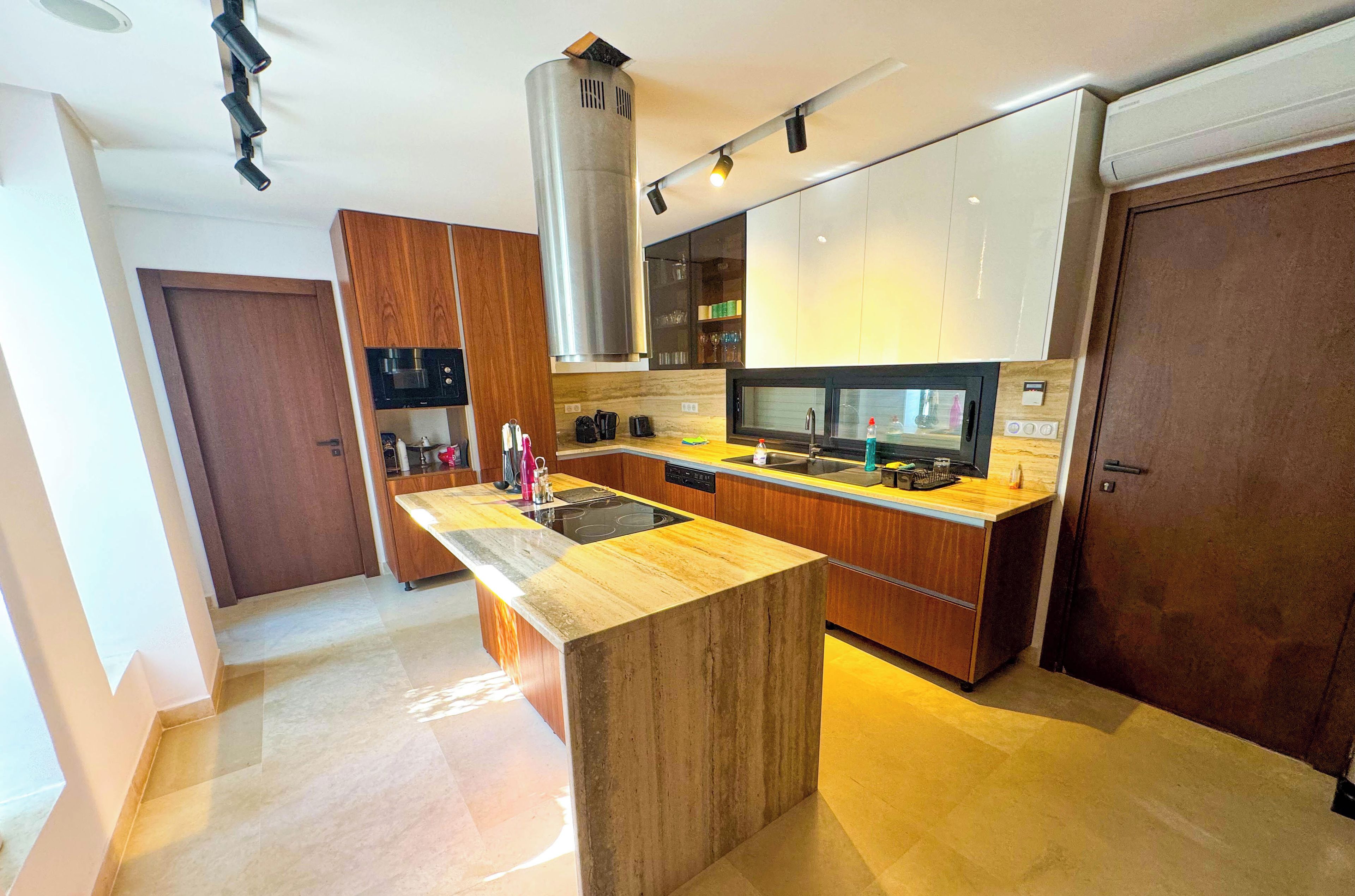 Una cocina moderna con una isla central, electrodomésticos de acero inoxidable y armarios de madera.
