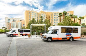 A bus parked in front of a hotel with a covered waiting area and palm trees. - Cozy 1-bedroom hotel in brilliant Las Vegas with AC and fitness room (Las Vegas)