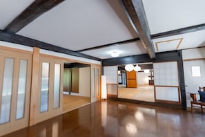 A traditional Japanese room with tatami flooring, sliding doors, and a wooden ceiling structure.