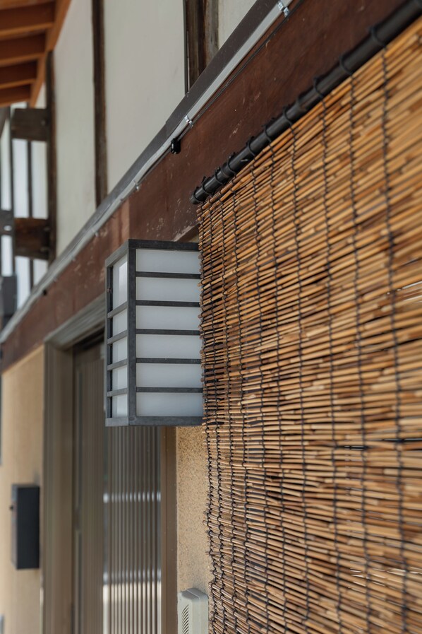 A building facade with a traditional wooden structure, a modern air conditioning unit, and a bamboo screen.