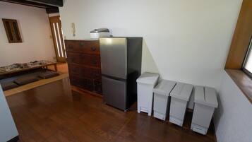 A compact kitchen with a refrigerator, a wooden dresser, and a bench.