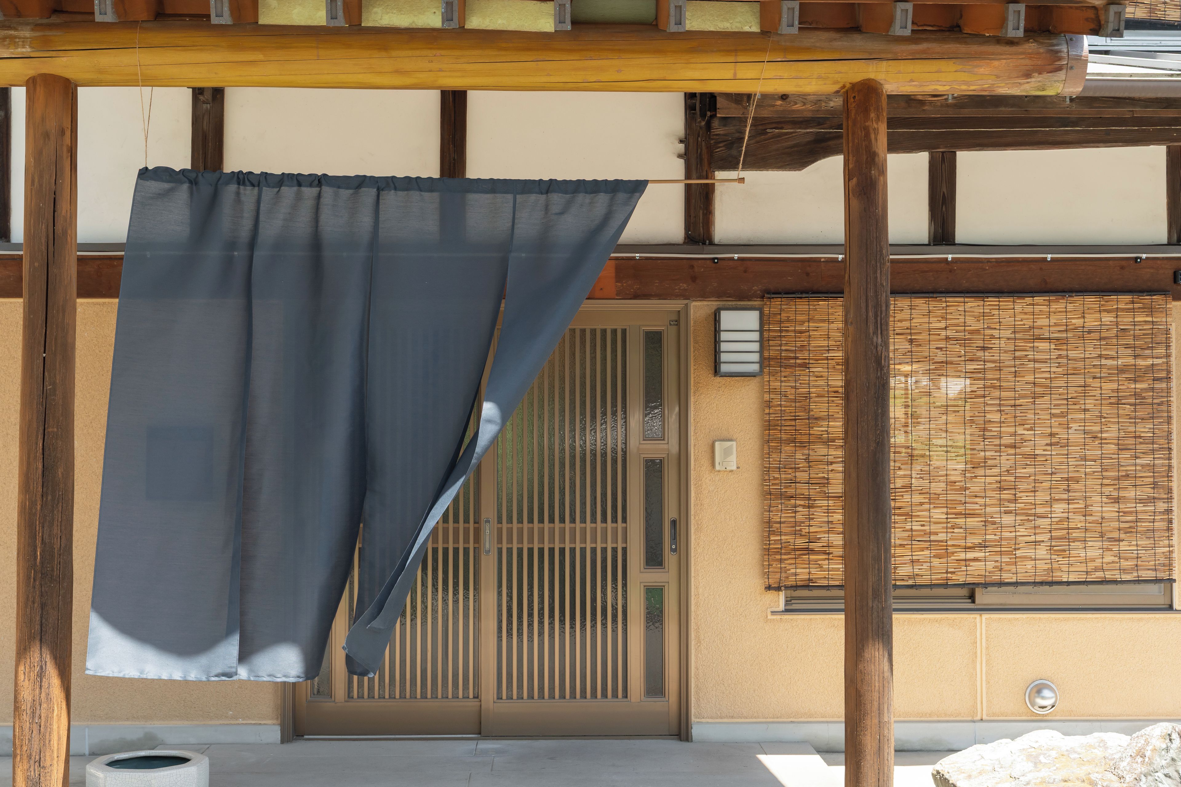 Un bâtiment japonais traditionnel, doté d’une structure en bois, d’une porte coulissante et d’un mur fait de matériaux tressés.