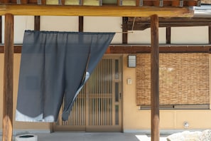 A traditional Japanese building with a wooden structure, a sliding door, and a woven wall.