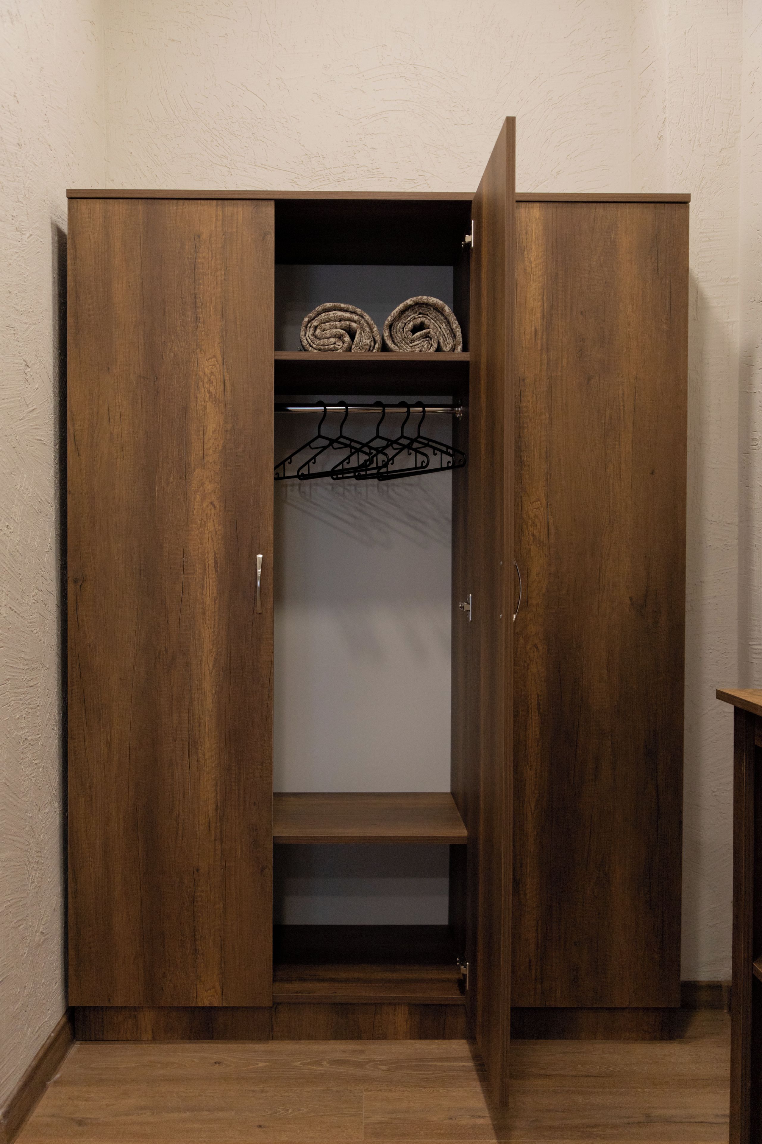 A wooden wardrobe with a hanging space and a shelf.