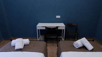 A room with two beds, a desk, and a chair.