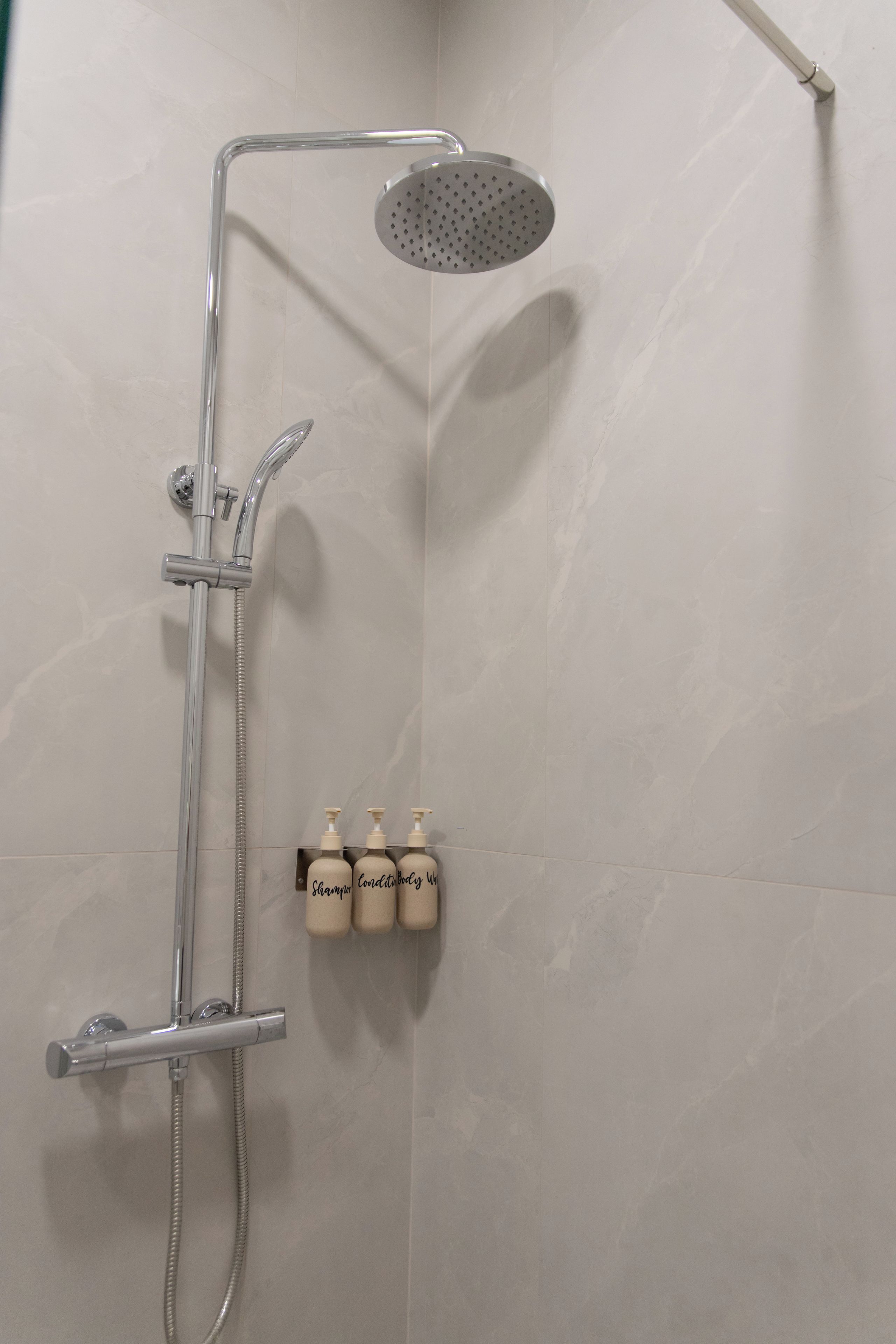 A shower with a handheld showerhead and a wall-mounted rain showerhead.