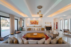 Amplio salón con una gran mesa de centro de madera, un sofá color beige y una lámpara moderna.