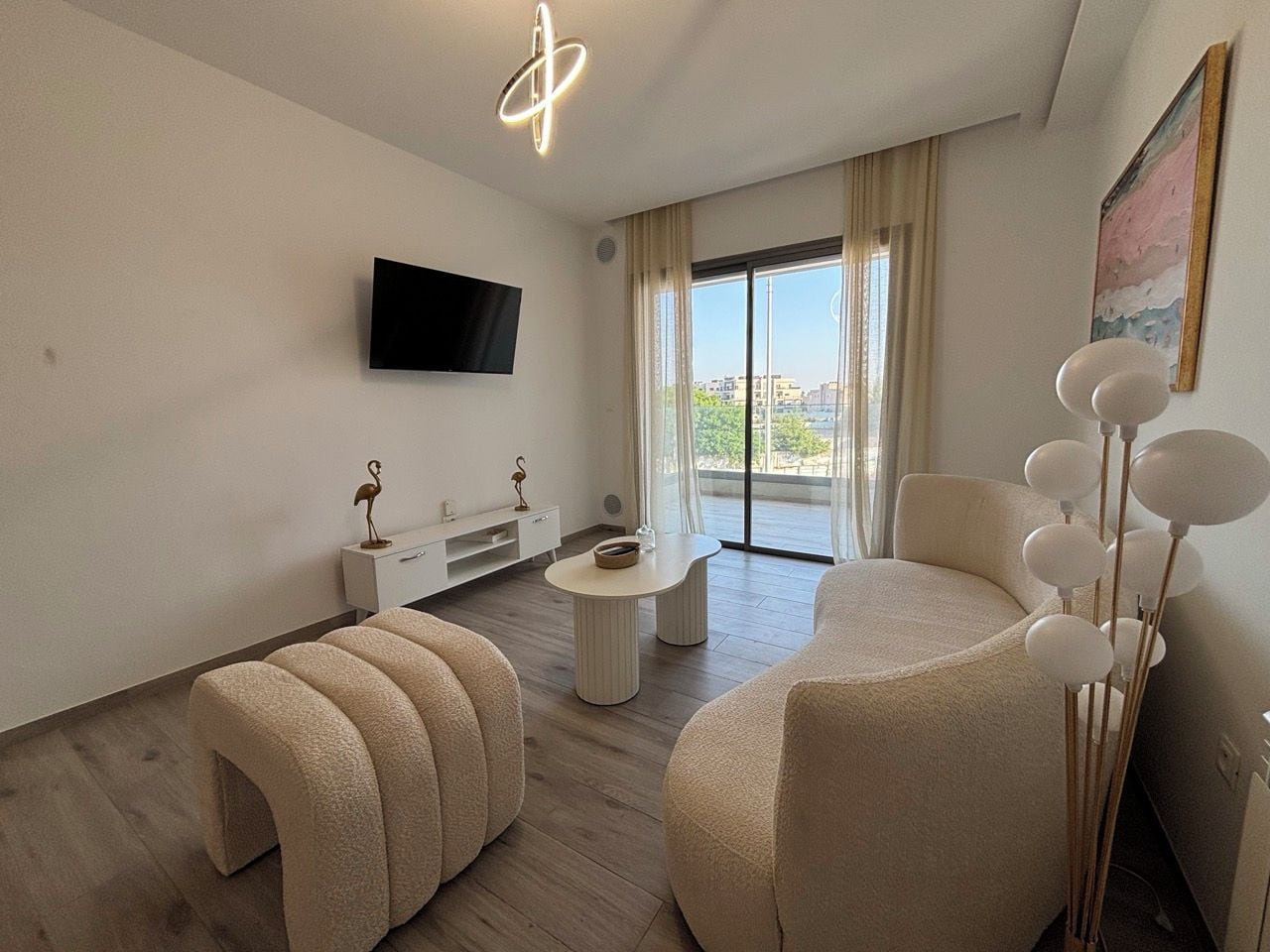 A modern living room with a flat-screen TV, a sofa, a coffee table, and a dining area.