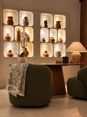 Ein modernes Interieur mit einer Couch, einer Lampe und einer Wand mit beleuchteter Keramik.