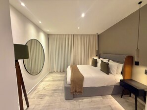 A modern bedroom with a large bed, a bedside table, a mirror, and a window with curtains. - Aurea Boutique Hotel & Spa (Rio de Janeiro)