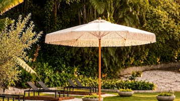Un jardí amb dues cadires relaxants, una taula i una ombrel·lera.