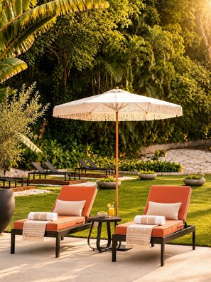 A garden with two lounge chairs, a table, and an umbrella. - Aurea Boutique Hotel & Spa (Rio de Janeiro)
