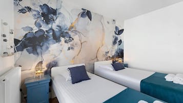A hotel room with two beds, a nightstand, a wall with a floral mural, and a ceiling fan.