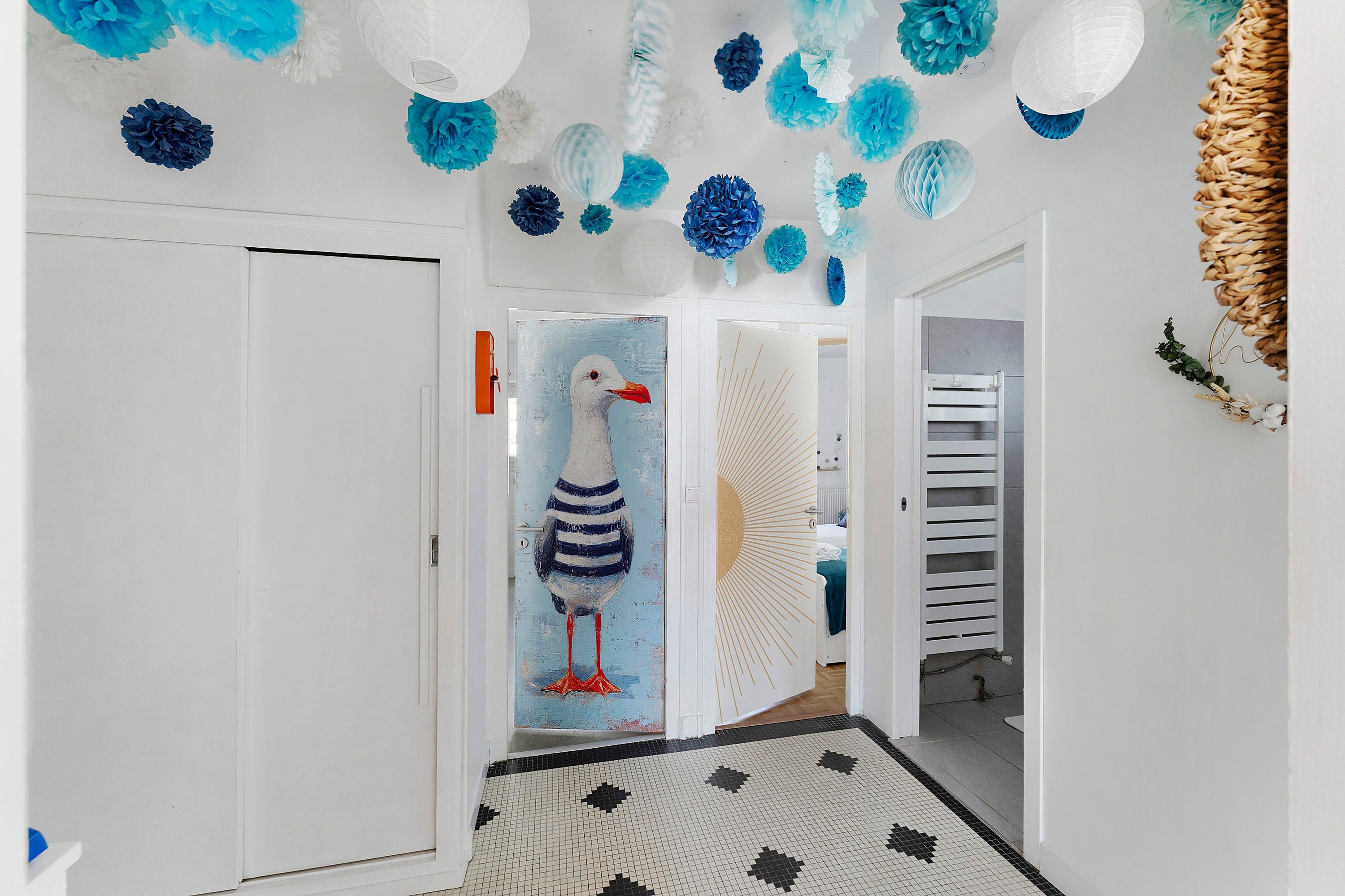 Een gang met een muurschildering van een zeemeeuw op een deur, een patroon vloer en decoraties aan het plafond.