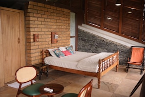 Een slaapkamer met een houten bed, een bakstenen muur, een stenen openhaard en een trap.