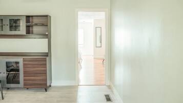 A room with a wooden cabinet, a chair, and a door leading to another room.