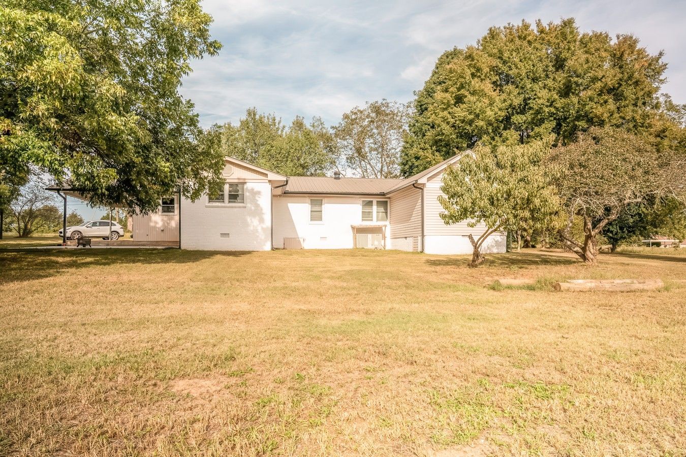 A single-story house with a front yard, a driveway, and a parked car.