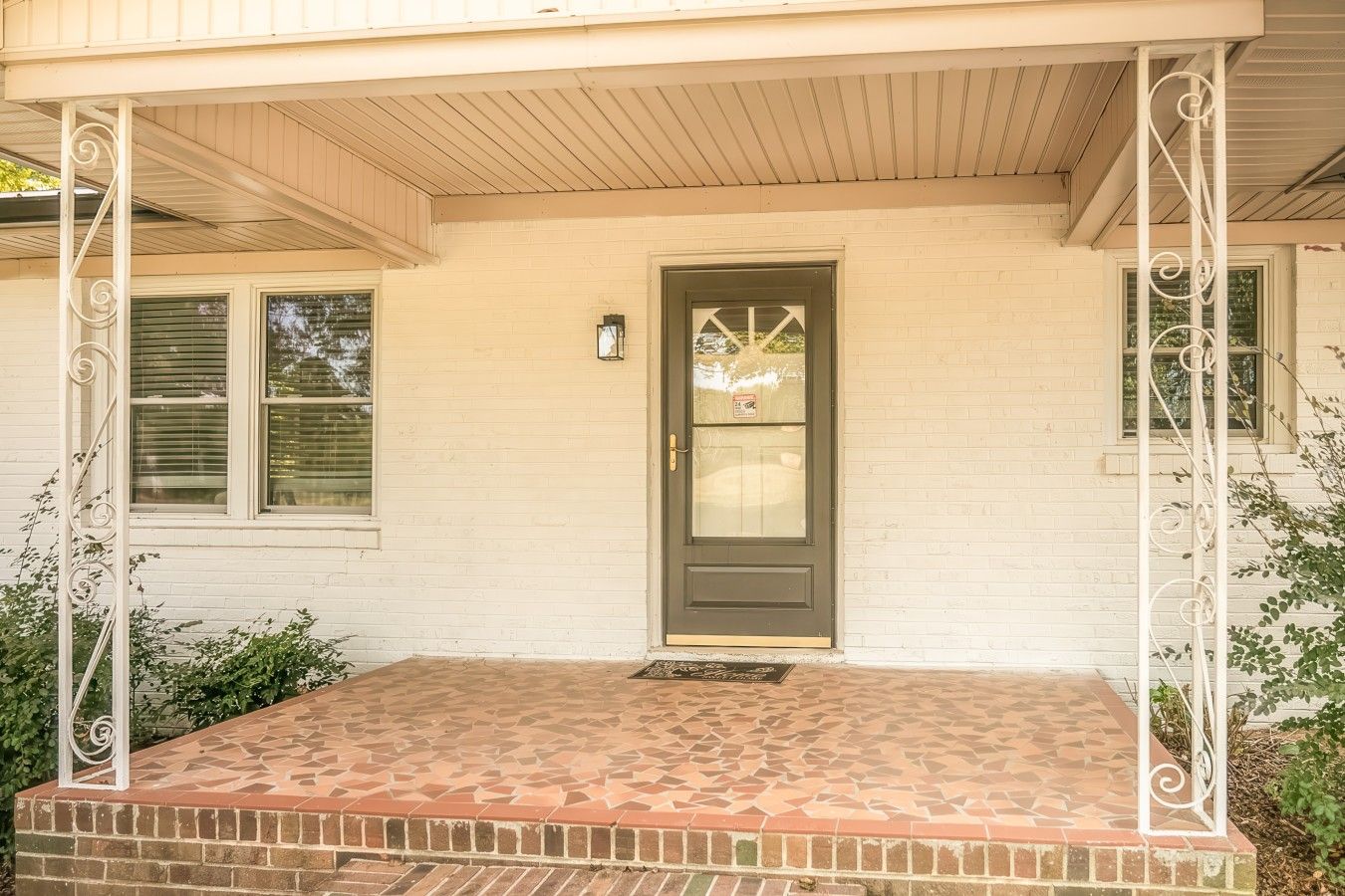 A house with a front porch, a dark front door, and a brick foundation.