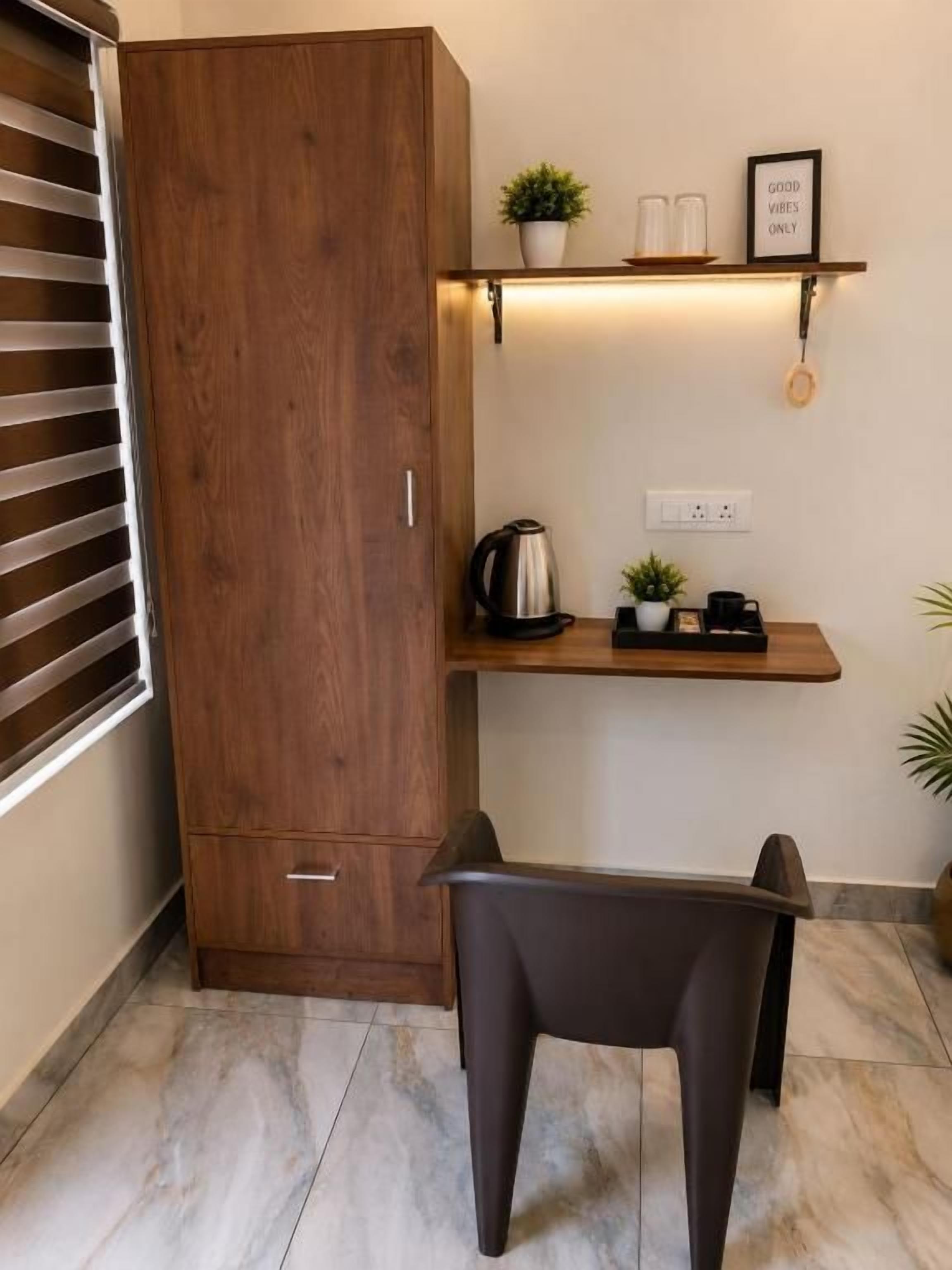 A compact kitchenette with a wooden cabinet, a countertop, and a chair.