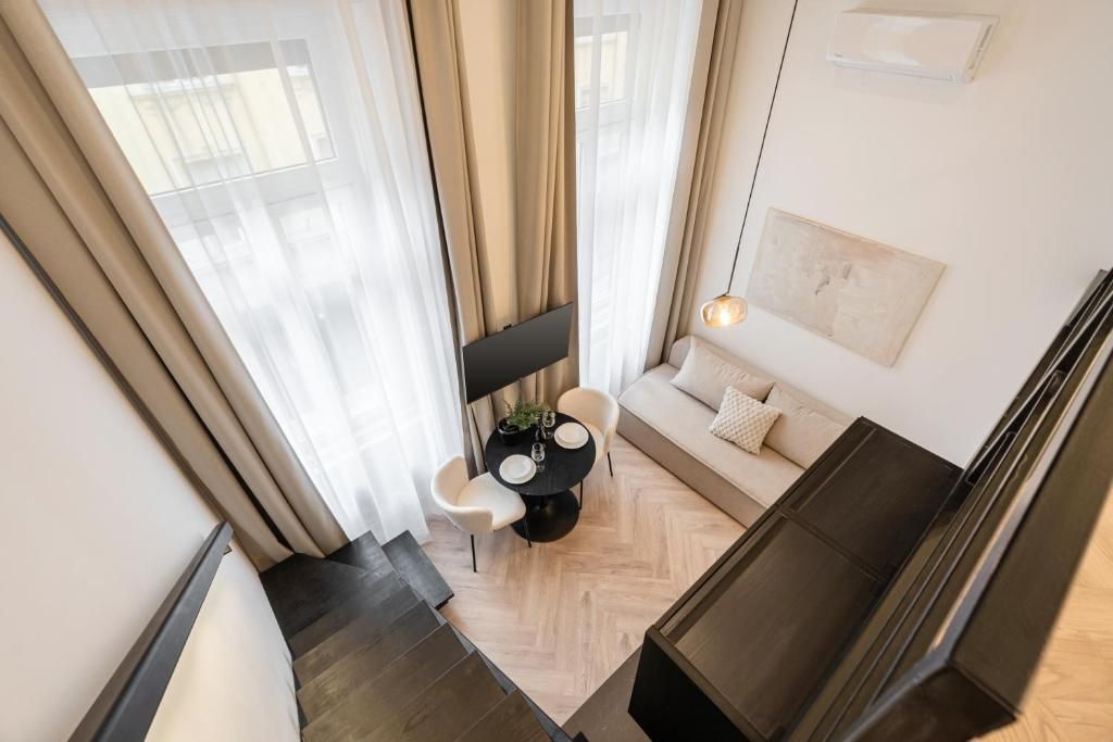 Una sala de estar moderna con un sofá, una mesa de comedor con sillas y un televisor montado en la pared.