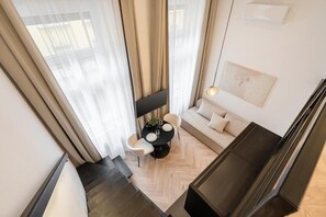 Una sala de estar moderna con un sofá, una mesa de comedor con sillas y un televisor montado en la pared.