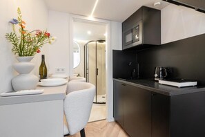 Una cocina moderna con microondas, cafetera y un florero con flores sobre la encimera.