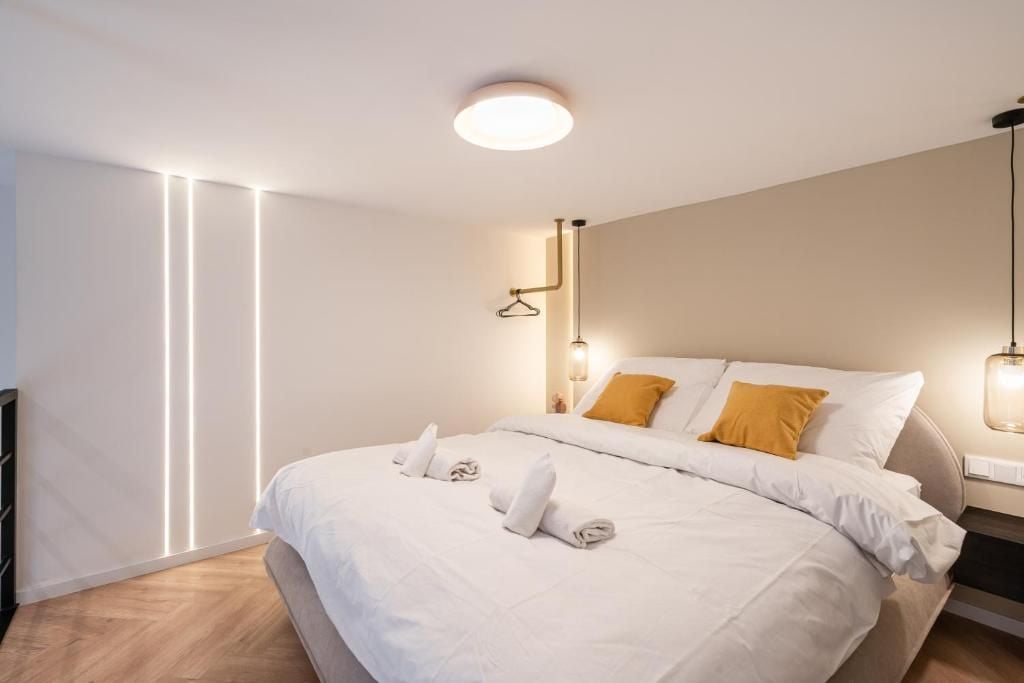 A modern hotel room with a neatly made bed, a hanging light fixture, and a wall-mounted light.