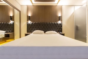 A modern hotel room with a large bed, a headboard with a tufted design, and bedside lamps. - Drops Motel Palhoça (Palhoça)