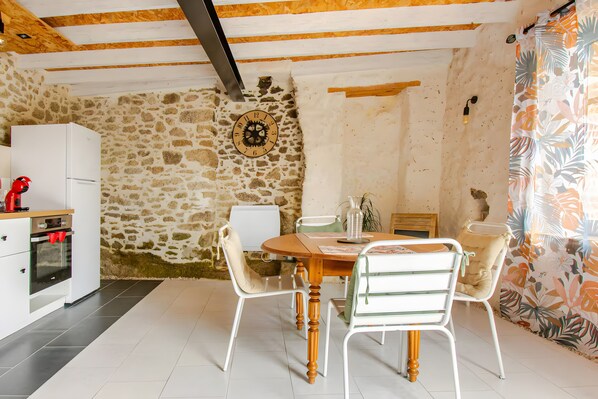 A dining area with a stone wall, a wooden ceiling, and a table with chairs.