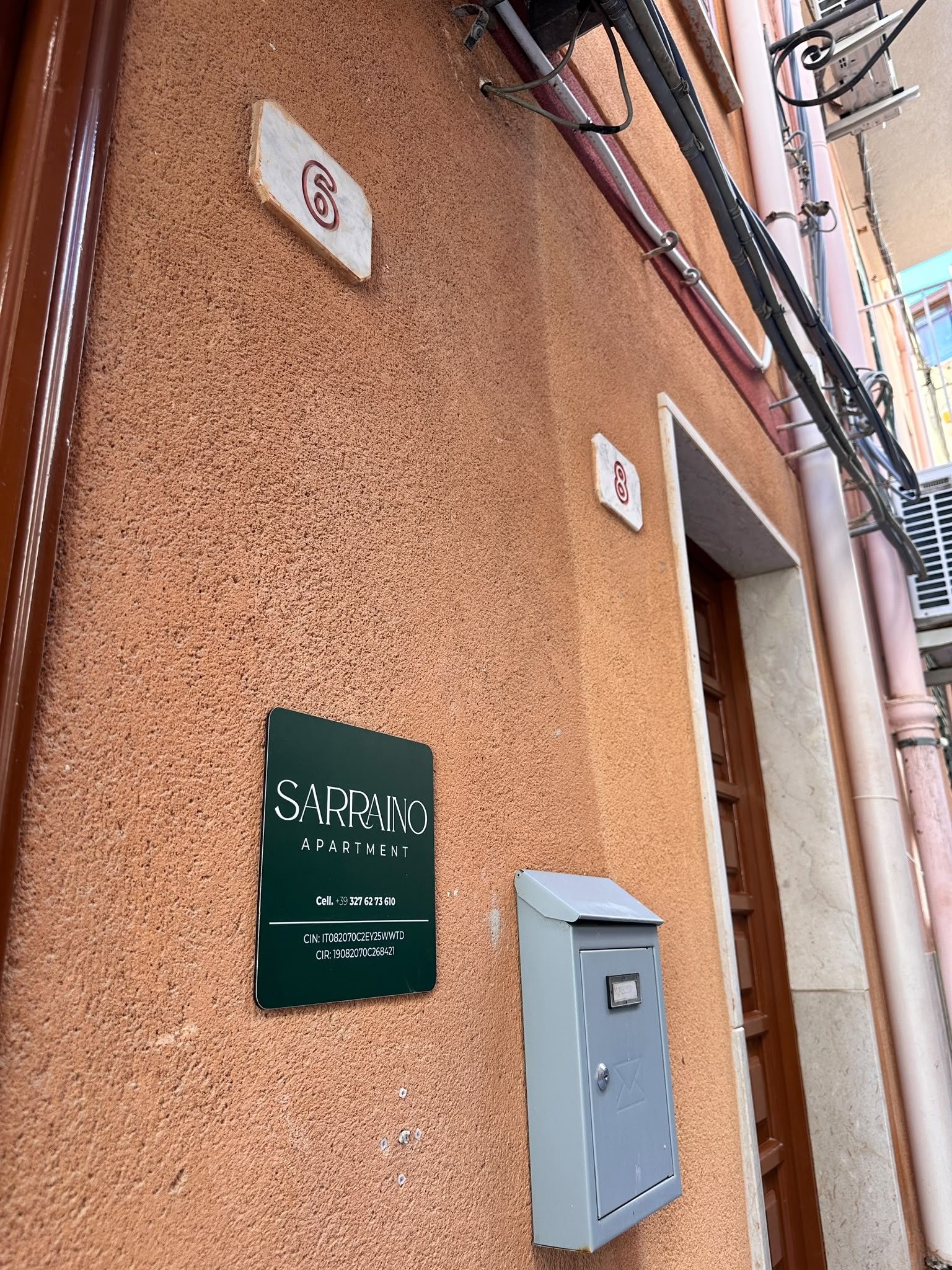 Eine Gebäudefassade mit einem Schild für 'SARRANO APARTMENT' und einem Stromzählerkasten.