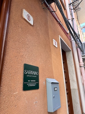Eine Gebäudefassade mit einem Schild für 'SARRANO APARTMENT' und einem Stromzählerkasten.