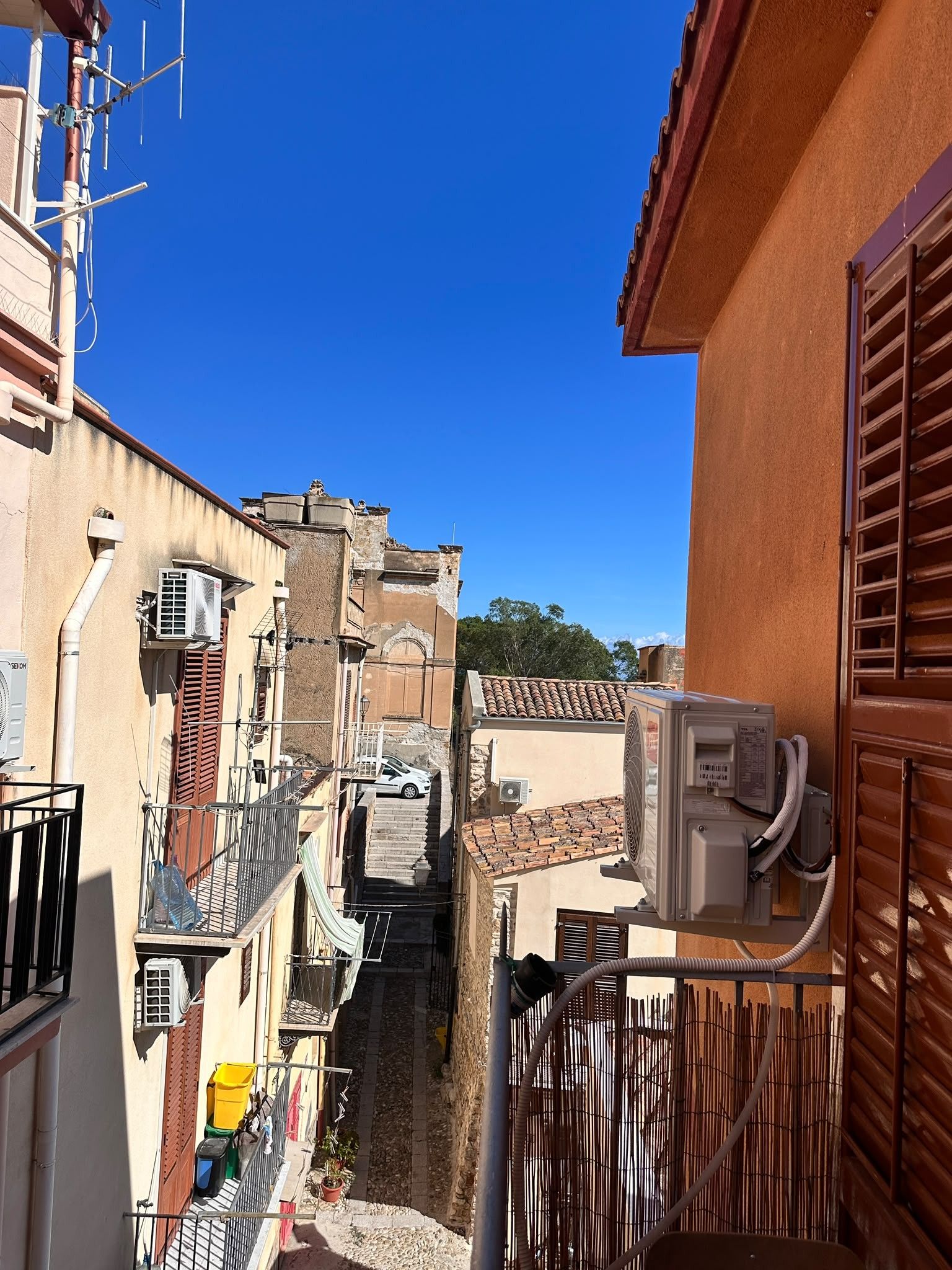 A narrow alleyway between buildings with a clear blue sky above.