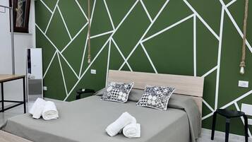 Ein modernes Schlafzimmer mit einem Kopfteil im geometrischen Muster, einem Bett mit grauer Bettdecke, zwei Kissen und ordentlich gefalteten Handtüchern auf dem Bett.