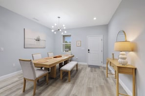 A dining room with a wooden table, chairs, and a chandelier.
