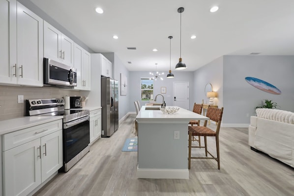 A modern kitchen with white cabinetry, stainless steel appliances, and a central island with seating.
