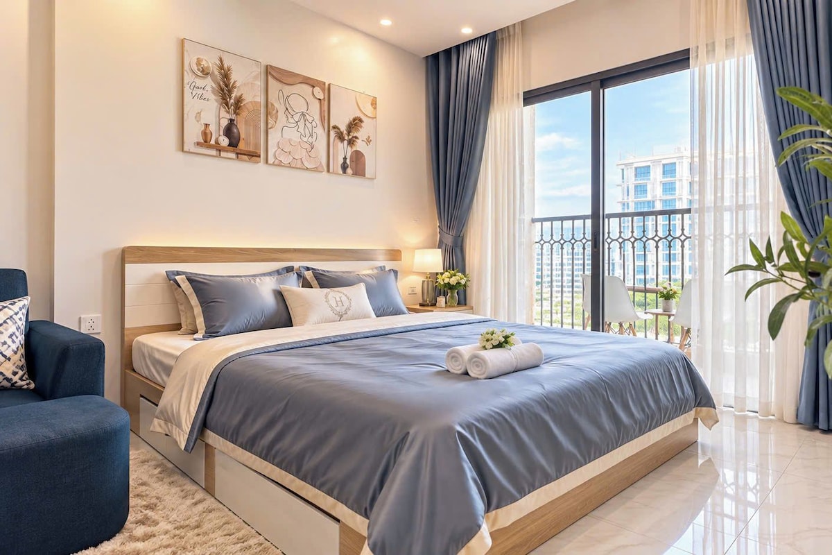 A modern bedroom with a large bed, a bedside table, a chair, and a potted plant.