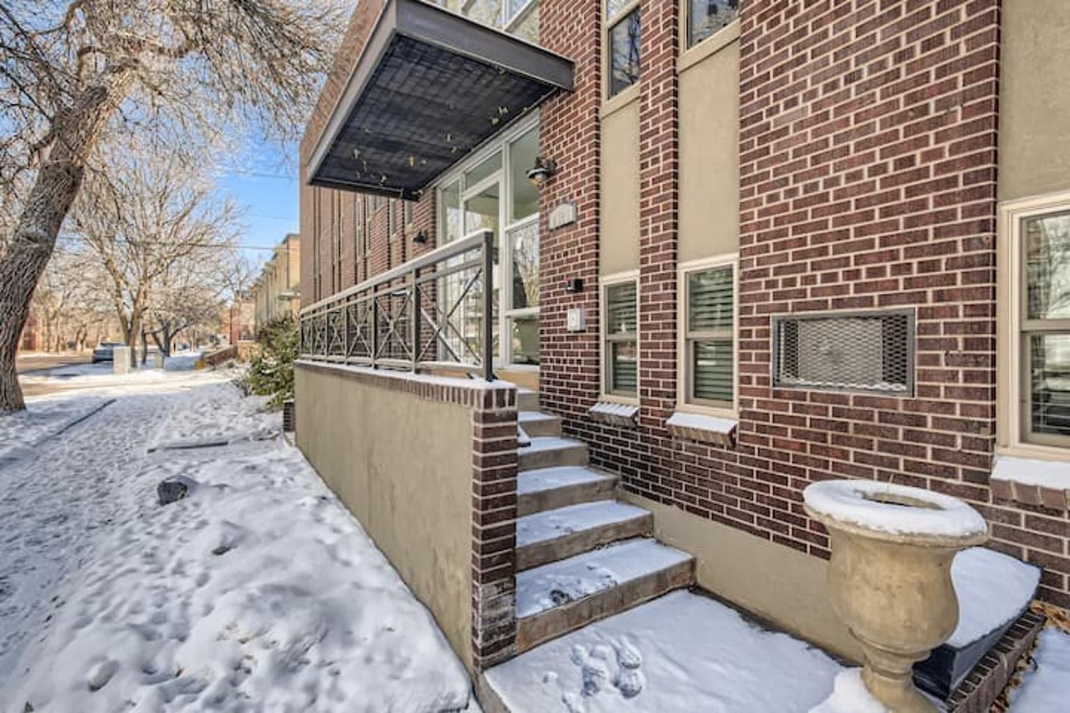 A residential building with a brick exterior, a covered porch, and a snow-covered ground.