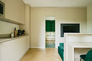 A modern kitchen with a built-in stove, a dining area with a white table, and a green sofa. - New Listing (Dervio)