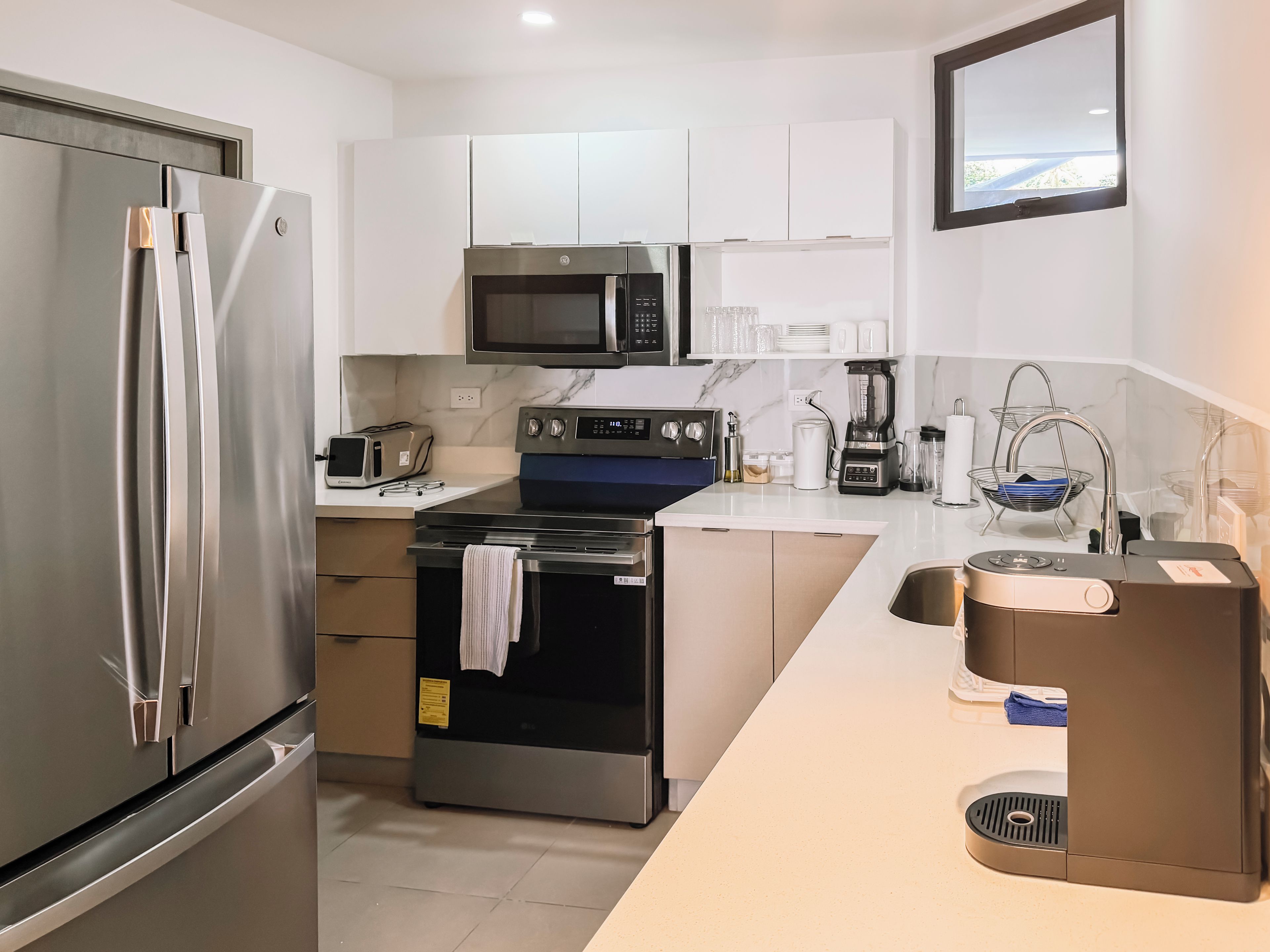 A modern kitchen with stainless steel appliances, a microwave, a toaster, and a coffee machine.