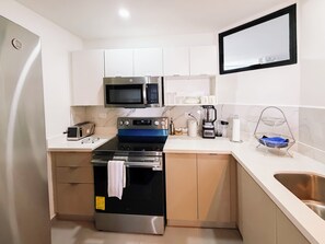 A compact kitchen with a microwave, oven, and toaster. - Urban Nest Lomas, 3 hab., vistas panorámicas, AC, balcón y 2 parqueos (San Salvador)