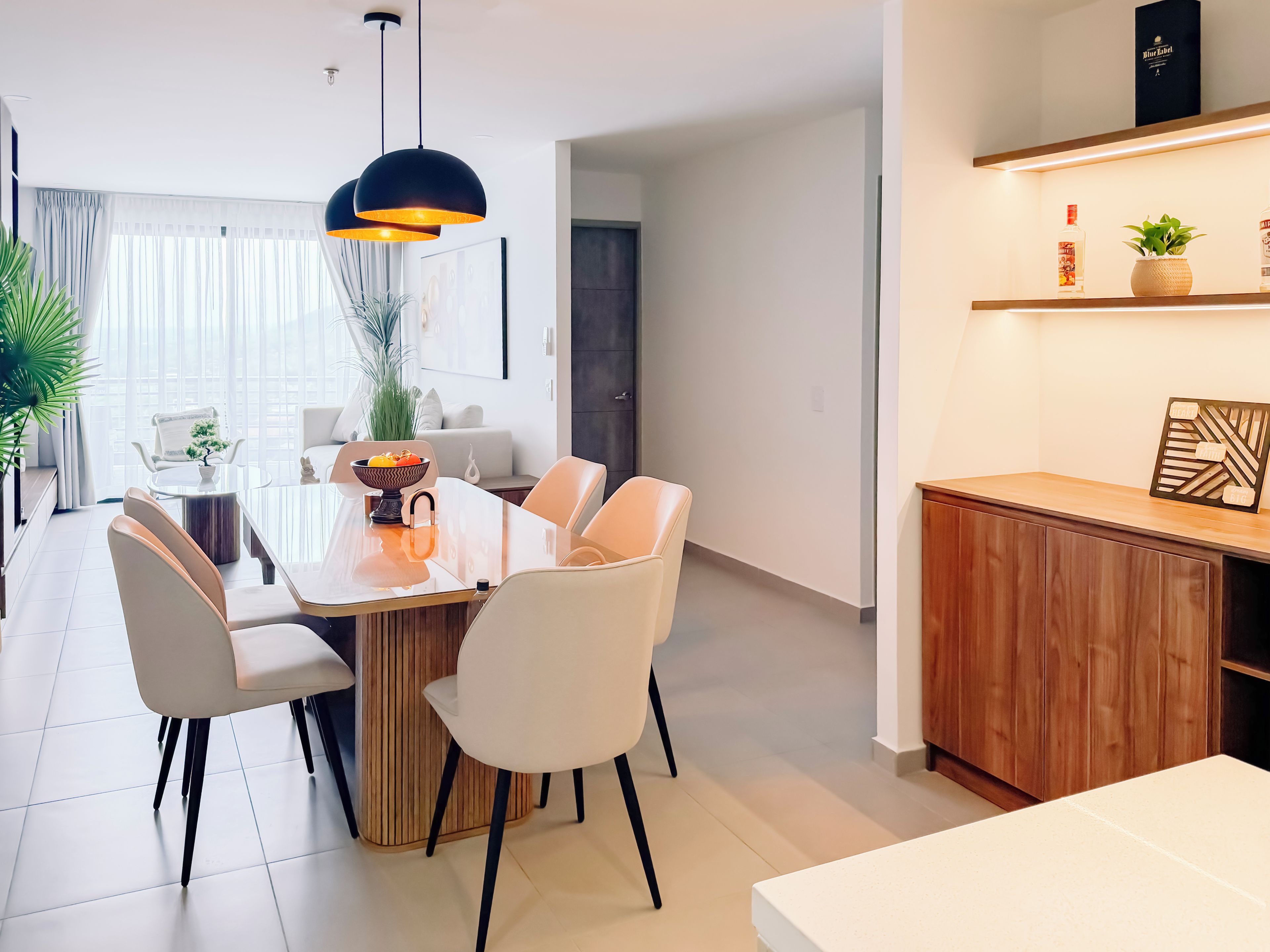 A modern dining area with a round table, white chairs, and pendant lighting.