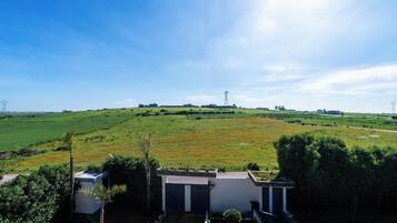 A residential property with a large open field, a small building with a garage, and a clear sky.