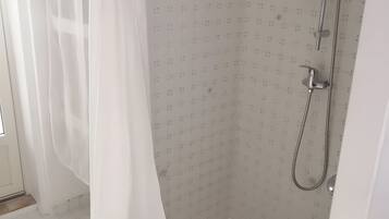 Un espace douche équipé d’un pommeau de douche et d’un rideau.