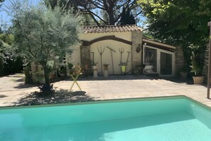 A pool area with a stone patio, a small building with a tiled roof, and various potted plants. - A fully renovated former sheep barn, located in the petite luberon region (Cheval-Blanc)