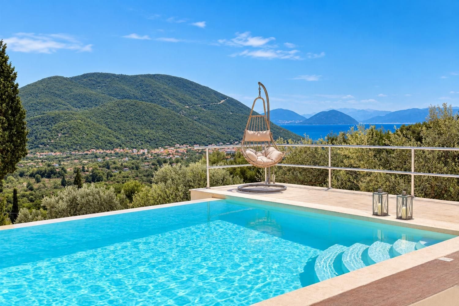 A pool with a hanging chair and a view of a mountainous landscape.