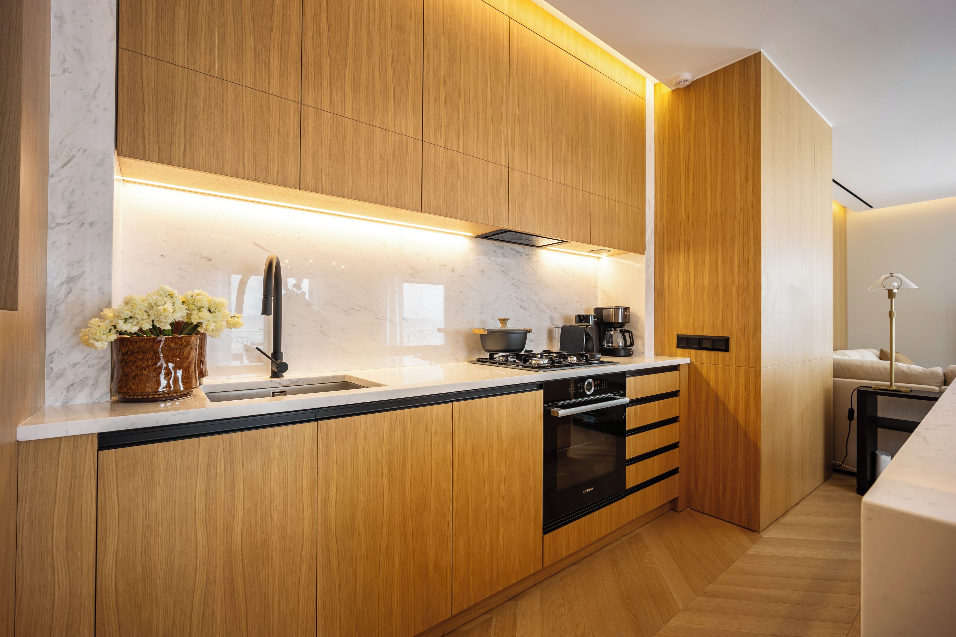 A modern kitchen with wooden cabinets, a marble countertop, and a Bosch oven.