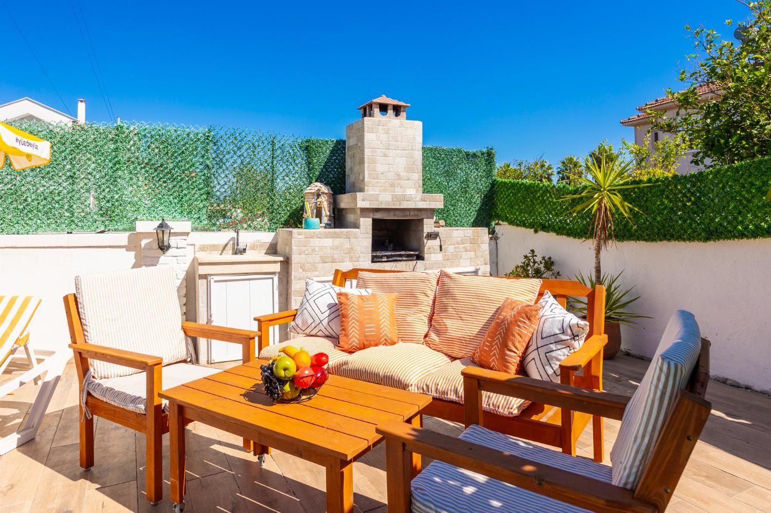 Un patio al aire libre con una chimenea de piedra, muebles de madera y un frutero.